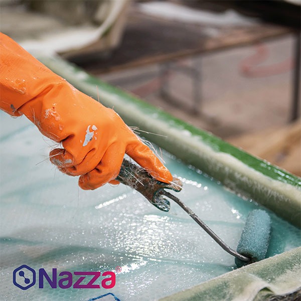Personne appliquant la résine au rouleau sur une pièce en fibre de verre pendant la stratification.